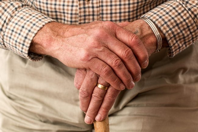 elderly hands crossed over a cane