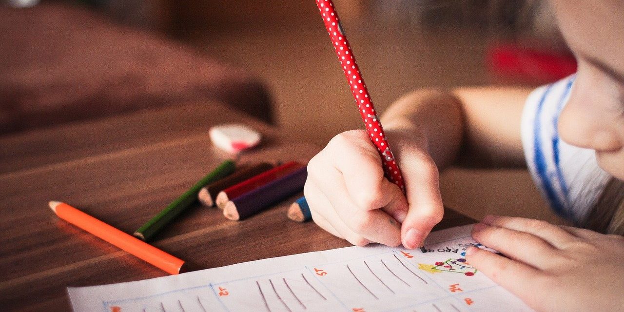 Child writing on a paper with a pencil