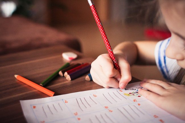 Child writing on a paper with a pencil