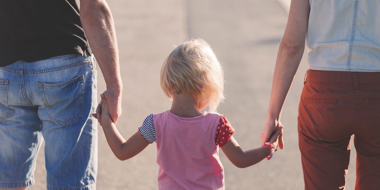 Little girl holding hands with two parents