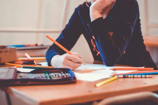 Student draws a picture at school desk