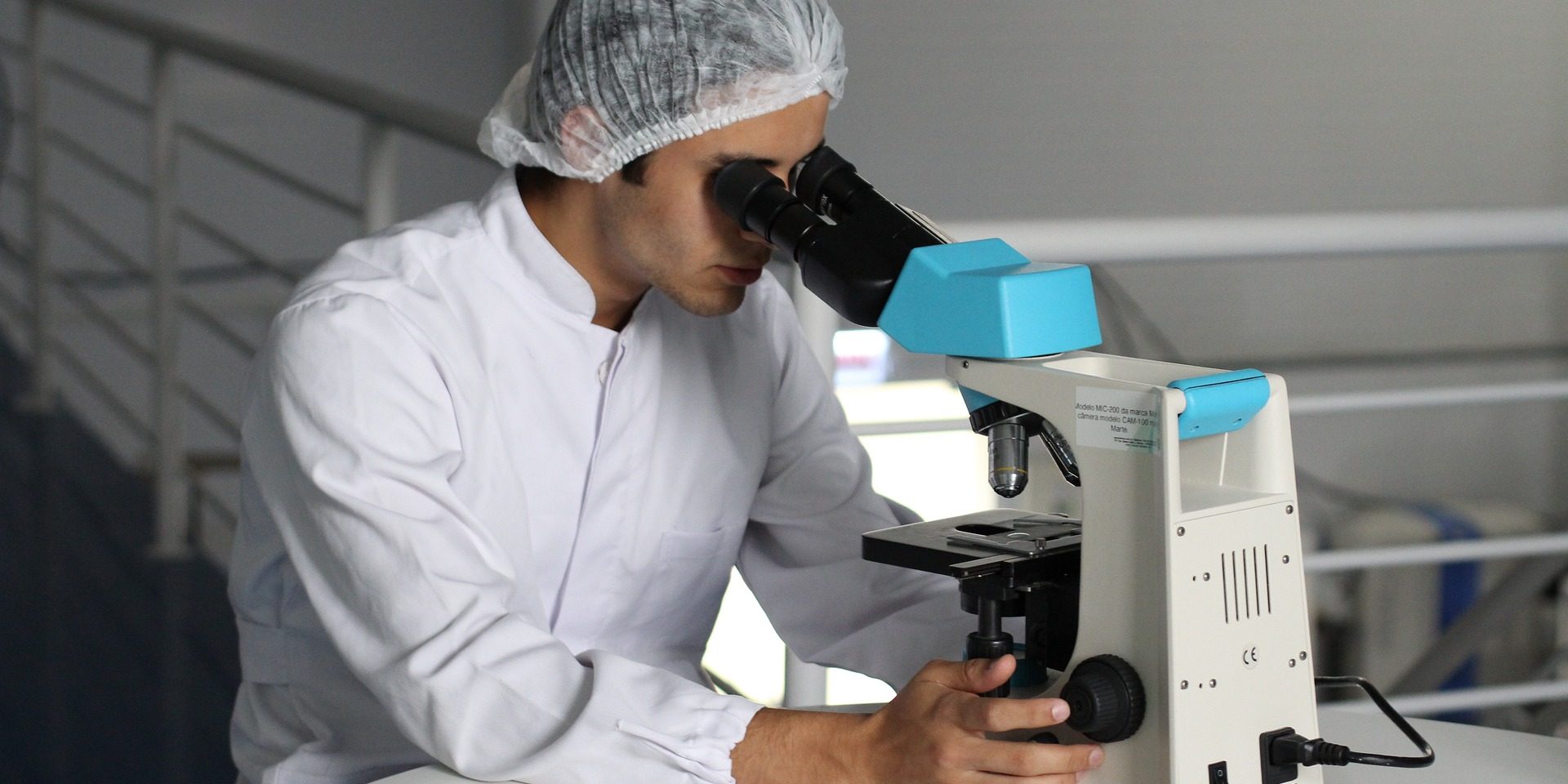 Scientist looks at microscope.