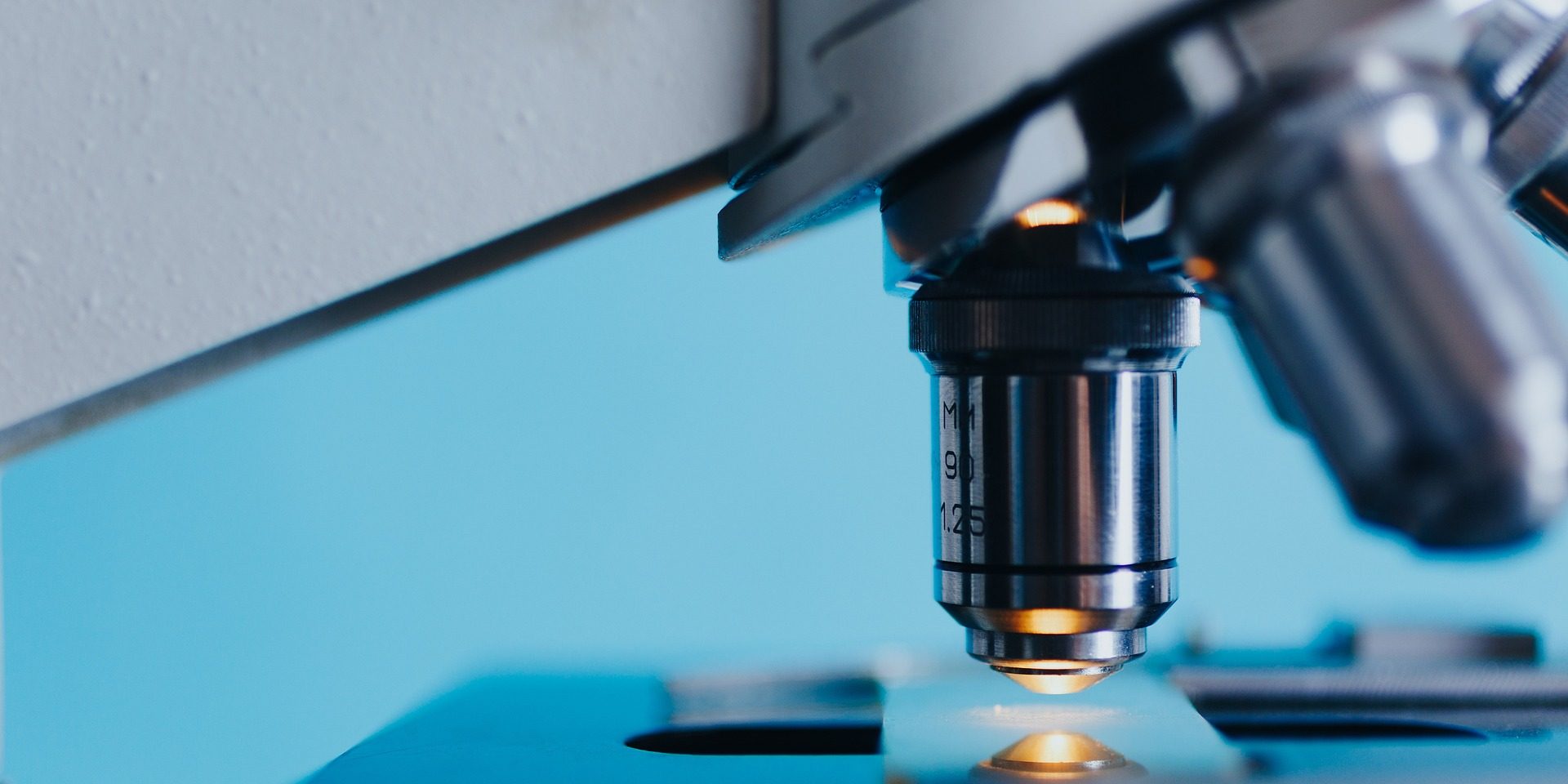 Microscope depicted with white light before a blue background.