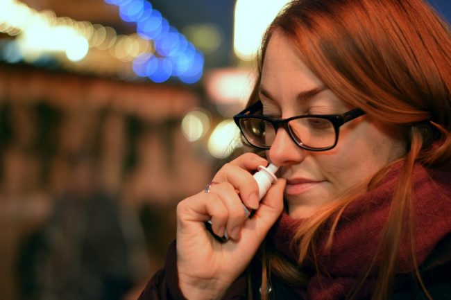 Woman uses nasal spray.