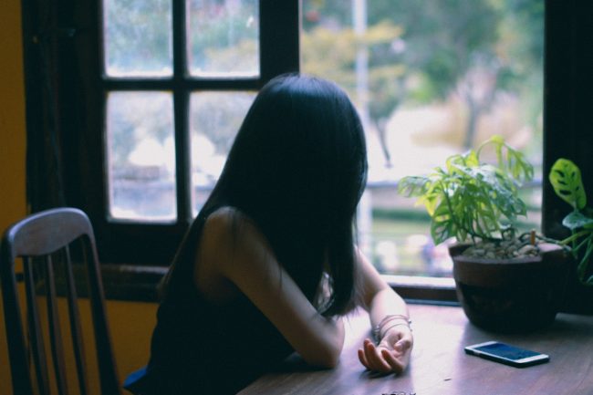 Woman sits at table looking out window